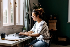 Young casually clothed woman working on laptop at home office stock photo